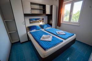 um quarto com uma cama com lençóis azuis e toalhas em Apartments Pavic em Vir