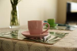 una taza de café rosa en un plato sobre una mesa en Wygodna kawalerka., en Kalisz