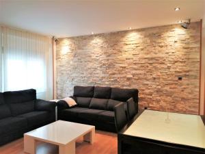 a living room with a couch and a brick wall at APARTAMENTO HUESCA in Huesca