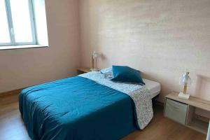 a bedroom with a bed with a blue comforter at Belle et grande maison proche plages débarquement in Mandeville-en-Bessin