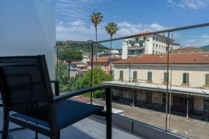 una silla en el balcón con vistas a la ciudad en Hotel Graziella en Arma di Taggia