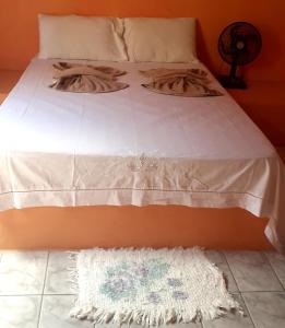 a bed with a white bedspread and a white rug on the floor at casa sarnambi in Atins