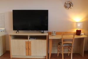 TV en un soporte con escritorio y silla en Ferienwohnung Boddenkieker bis 4 Personen, Sagard-Neddesitz, 70m2 en Sagard
