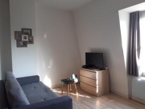a living room with a blue couch and a tv at Au coeur des remparts, residence du château* in Gravelines