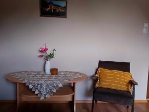 una mesa con un jarrón de flores y dos sillas en Luna Apartman en Gyula
