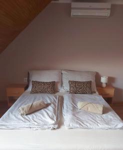 Una cama con sábanas blancas y almohadas. en Luna Apartman en Gyula