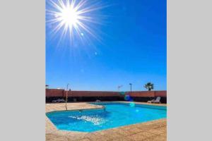 una piscina con el sol en el cielo en Sea View Loft, en Playa Blanca