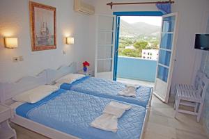 a bedroom with a blue bed and a balcony at St.George Valsamitis in Katapola