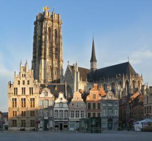 un grand bâtiment avec une cathédrale en arrière-plan dans l'établissement BnB De Koepoort, à Malines