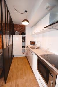 a kitchen with white cabinets and a black refrigerator at Appartement et Garage au Cœur de l'Isle in LʼIsle-sur-la-Sorgue