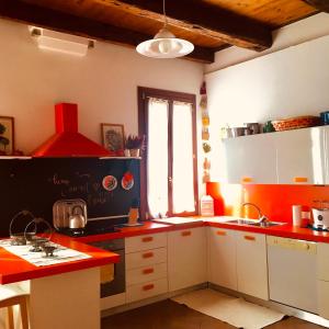 una cocina con armarios blancos y encimeras rojas en La Casa Del Pittore, en Venecia