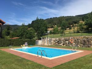 a swimming pool in a yard with a rock wall at PRECIOSO CHALET JUNTO A POTES CON PISCINA-4 Hab,3 Baños in Ojedo