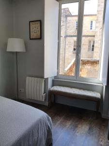 a bedroom with a window and a bed and a lamp at Le triangle d or in Bordeaux