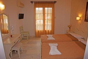 a bedroom with two beds and a vanity and a mirror at St.George Valsamitis in Katapola