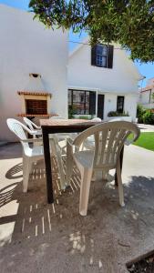 una mesa de madera y 2 sillas blancas frente a una casa en The Beach House, en Praia da Barra