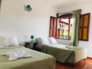 two beds in a room with a window at Hotel Torogoz in Granada