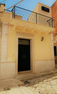 ein Gebäude mit einer schwarzen Tür und einem Balkon in der Unterkunft Apartment Piazza del Popolo in San Pietro Vernotico