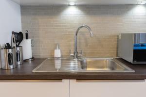 a kitchen with a stainless steel sink in a kitchen at Executive City Centre Apartment with Gated Parking and Stylish Rooms includes Privacy and Space with Luxury Feel plus Courtyard Garden in Amazing Location and Very Highly Rated in Peterborough