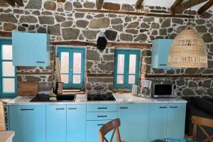 uma cozinha com armários azuis e uma parede de pedra em Sfeervol gerenoveerd huis in oud Grieks dorp em Sikia