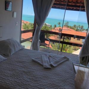 a bed with two towels on it with a view of the ocean at Pousada Brisa da Canoa in Canoa Quebrada