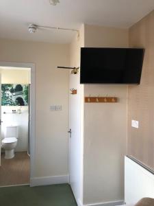 a bathroom with a toilet and a television on the wall at The Aberdeen Arms Hotel in Tarves