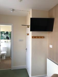 a bathroom with a toilet and a television on the wall at The Aberdeen Arms Hotel in Tarves