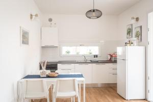 a white kitchen with a table and a refrigerator at Appartamento nuovo da Lilly con terrazza tra centro e mare in Fano