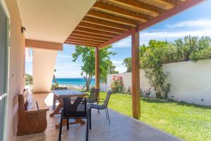 un patio con mesa, sillas y el océano en Villa Eleftheria, en Vitalades