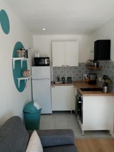 eine kleine Küche mit weißen Schränken und einer blauen Couch in der Unterkunft Appartement cocoon à Courseulles sur Mer in Courseulles-sur-Mer