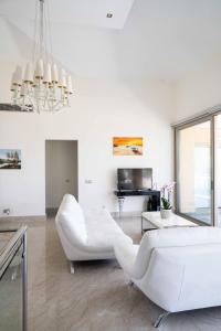 uma sala de estar com mobiliário branco e um piano em Villa Pandora - 4 Bedroom Luxury Beach Front Villa with Private Pool em Pólis