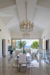 uma sala de jantar com uma mesa e cadeiras e um lustre em Villa Pandora - 4 Bedroom Luxury Beach Front Villa with Private Pool em Pólis