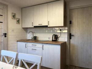 a kitchen with white cabinets and a table and chairs at Apartamenty Chris in Augustów