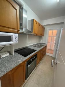 Una cocina con gabinetes de madera y un horno de estufa. en Piso a 150 mts de la playa con espectacular terraza y WIFI, en Tossa de Mar 9 fotos más