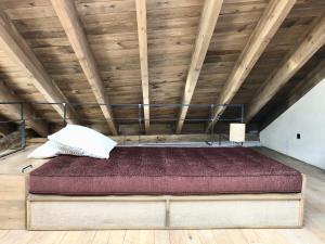 a bed in a room with a wooden ceiling at El pajar de abajo - Pedraza - in La Alameda