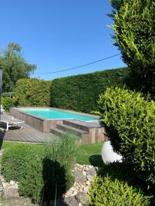 a swimming pool in a garden with bushes at Pont du Chalon Hôtel and Restaurant in Margès