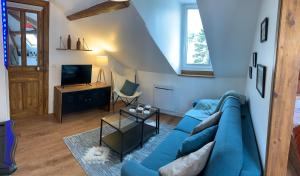 a living room with a blue couch and a tv at Appart LH L'Estuaire - F2 vue mer proximité plage in Le Havre