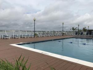 een groot zwembad met stoelen en een terras bij Assateague House II in Ocean City