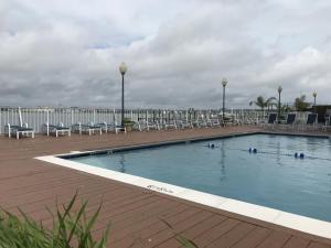 una grande piscina con sedie e una terrazza di Assateague House II a Ocean City
