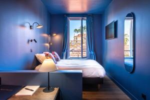 Dormitorio azul con cama y ventana en Boutique Hotel Nice Côte d'azur, en Niza