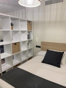 um quarto com prateleiras brancas e uma cama com uma almofada preta em Apartamentos San Lazaro em Santiago de Compostela