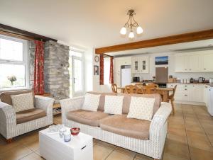 a living room with a couch and chairs and a kitchen at Fron Fawr in Nefyn