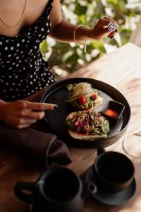 a woman holding a plate of food on top of a table at Encantada Tulum in Tulum