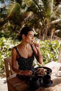 Encantada Tulum في تولوم: امرأة تجلس على طاولة مع وعاء من الطعام