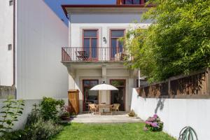 Casa blanca con mesa y sombrilla en Oporto MyWish City Central Apartment with Private Garden, en Oporto