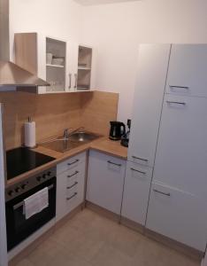 a small kitchen with white cabinets and a sink at Ferienwohnung am Kurwald in Bad Lippspringe in Bad Lippspringe