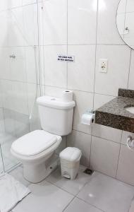 a white toilet sitting next to a white sink at Pousada Berro D'água in Cananéia