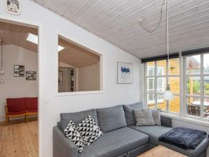 uma sala de estar com um sofá cinzento e janelas em 8 person holiday home in R m em Kongsmark