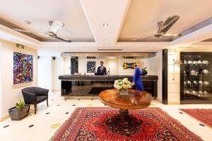 a woman standing in a lobby with a table and a piano at Best Western Plus Embassy Hotel in Athens