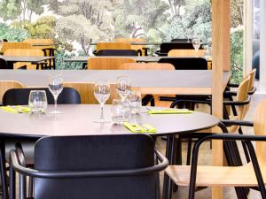 un restaurante con mesas y sillas y copas de vino. en Hôtel ibis Styles Montargis Arboria, en Pannes