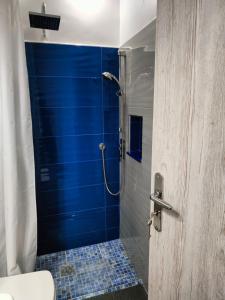 a bathroom with a shower with a blue wall at Sea Sound Haraki apartment in Haraki